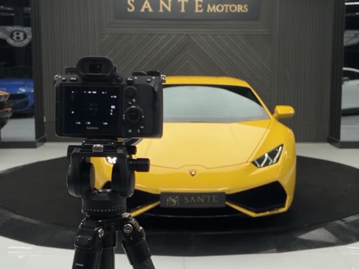 A camera on a tripod in front of a Lamborghini Huracán on a YilPlat car turntable at Sante Motors